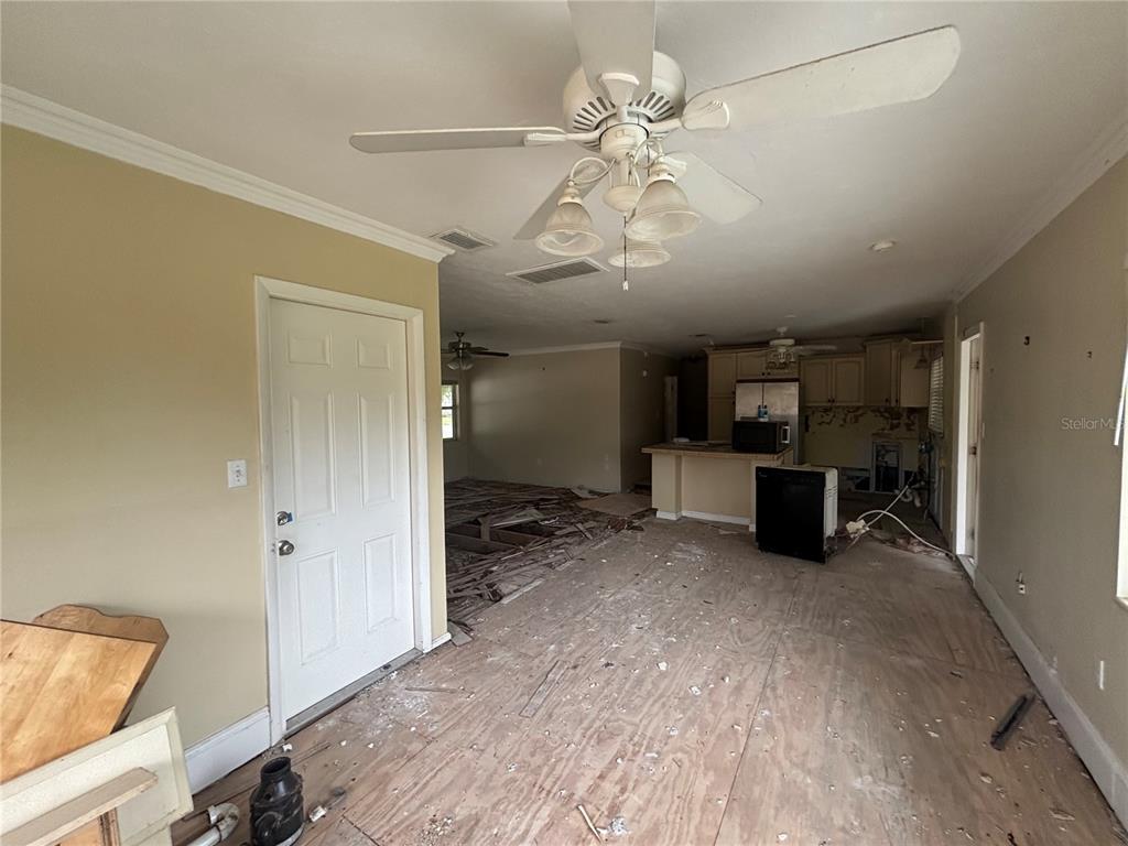 An interior view of a room under renovation with exposed plywood subflooring and a ceiling fan — 5620 2ND AVENUE DRIVE W, BRADENTON, FL