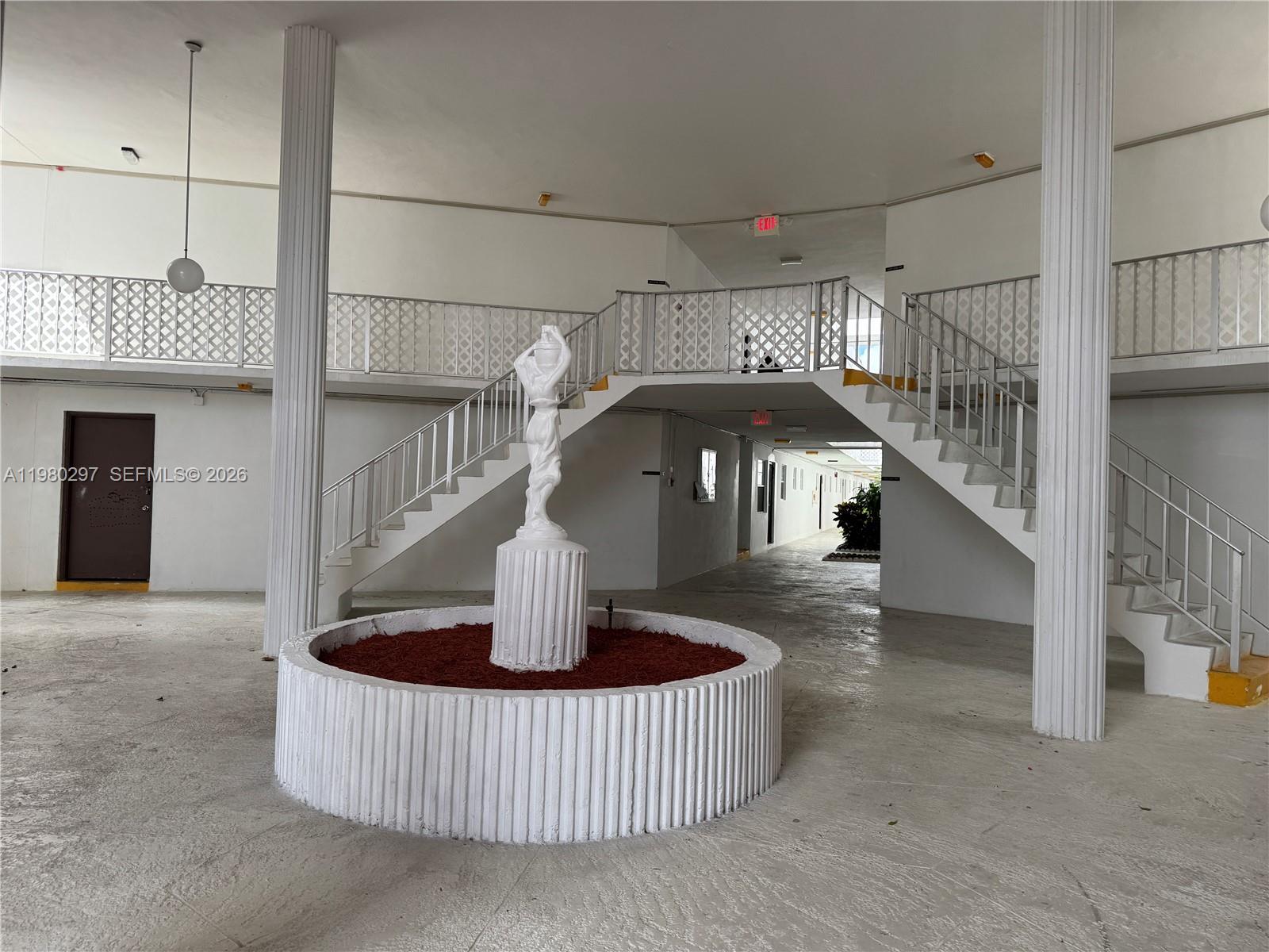A central statue fountain stands in an open-air courtyard with white columns and staircases — 6507 Winfield Blvd, Margate FL 33063, MARGATE, FL