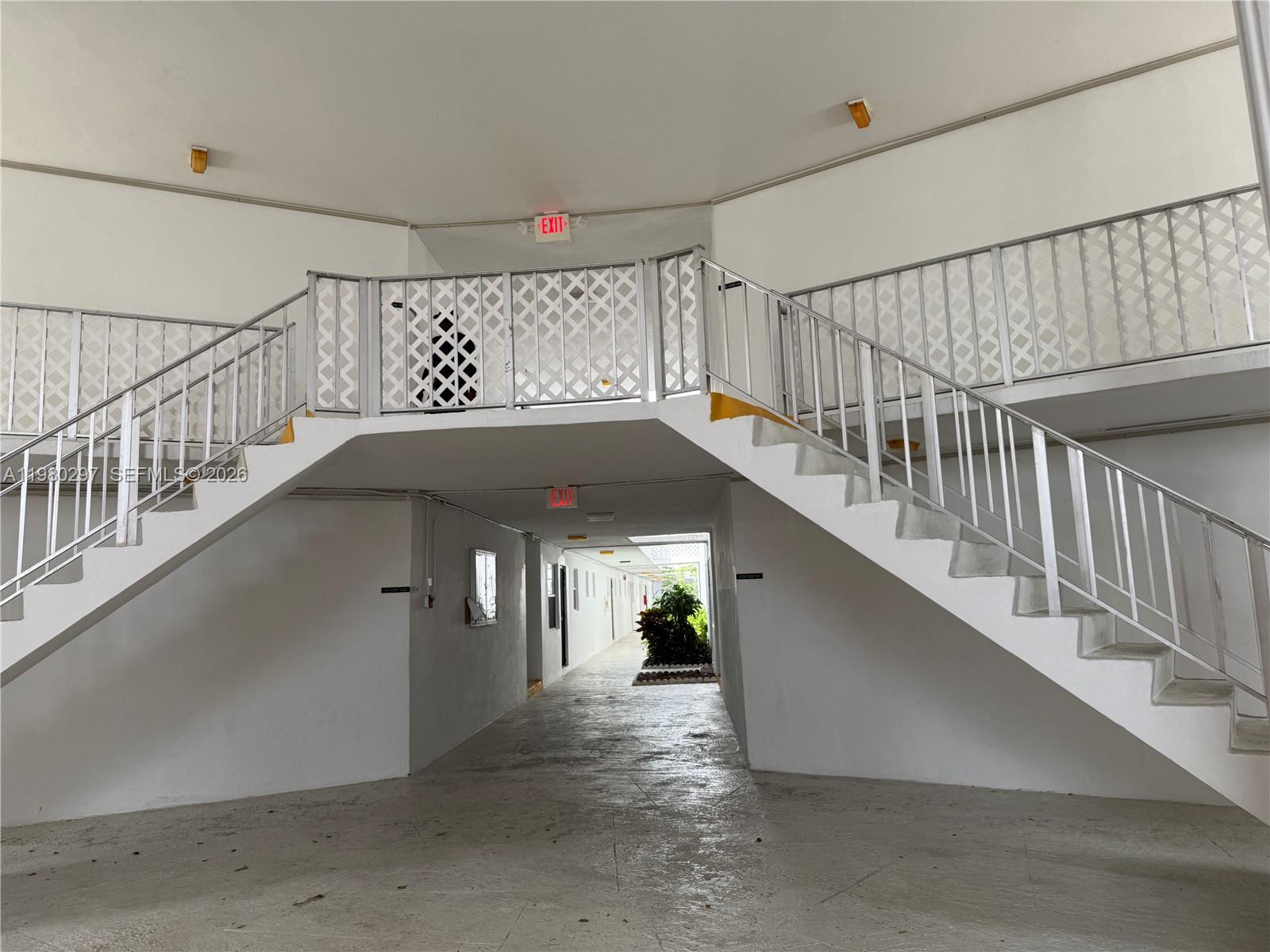 An outdoor stairwell connects two levels of a white building with a central hallway — 6507 Winfield Blvd, Margate FL 33063, MARGATE, FL