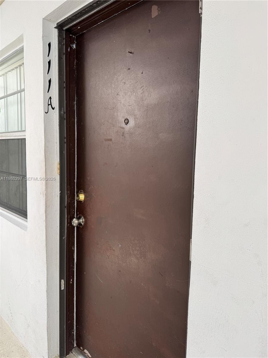 A brown front door with a peephole and a silver handle is labeled 1111A — 6507 Winfield Blvd, Margate FL 33063, MARGATE, FL