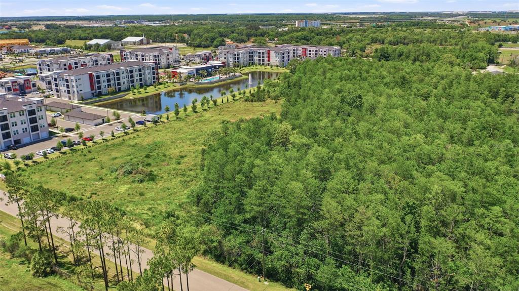An aerial view shows a large wooded lot adjacent to a pond and apartment complex — 6385 BETH ROAD, ORLANDO, FL