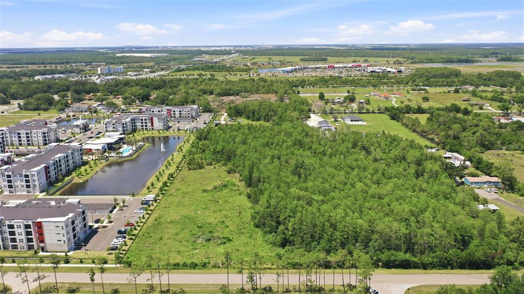 An aerial view shows a large, wooded plot of land adjacent to apartment complexes and ponds — 6385 BETH ROAD, ORLANDO, FL
