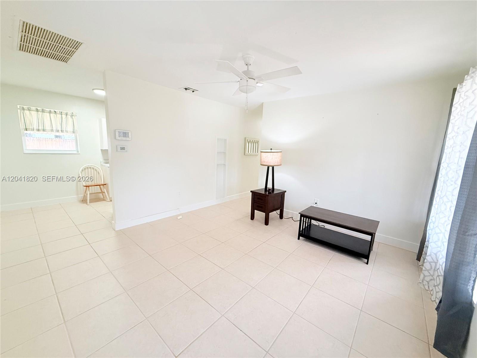 A living room with white walls, tile flooring, a ceiling fan, and a small table — 1311 N 69th Ave, Hollywood FL 33024, HOLLYWOOD, FL