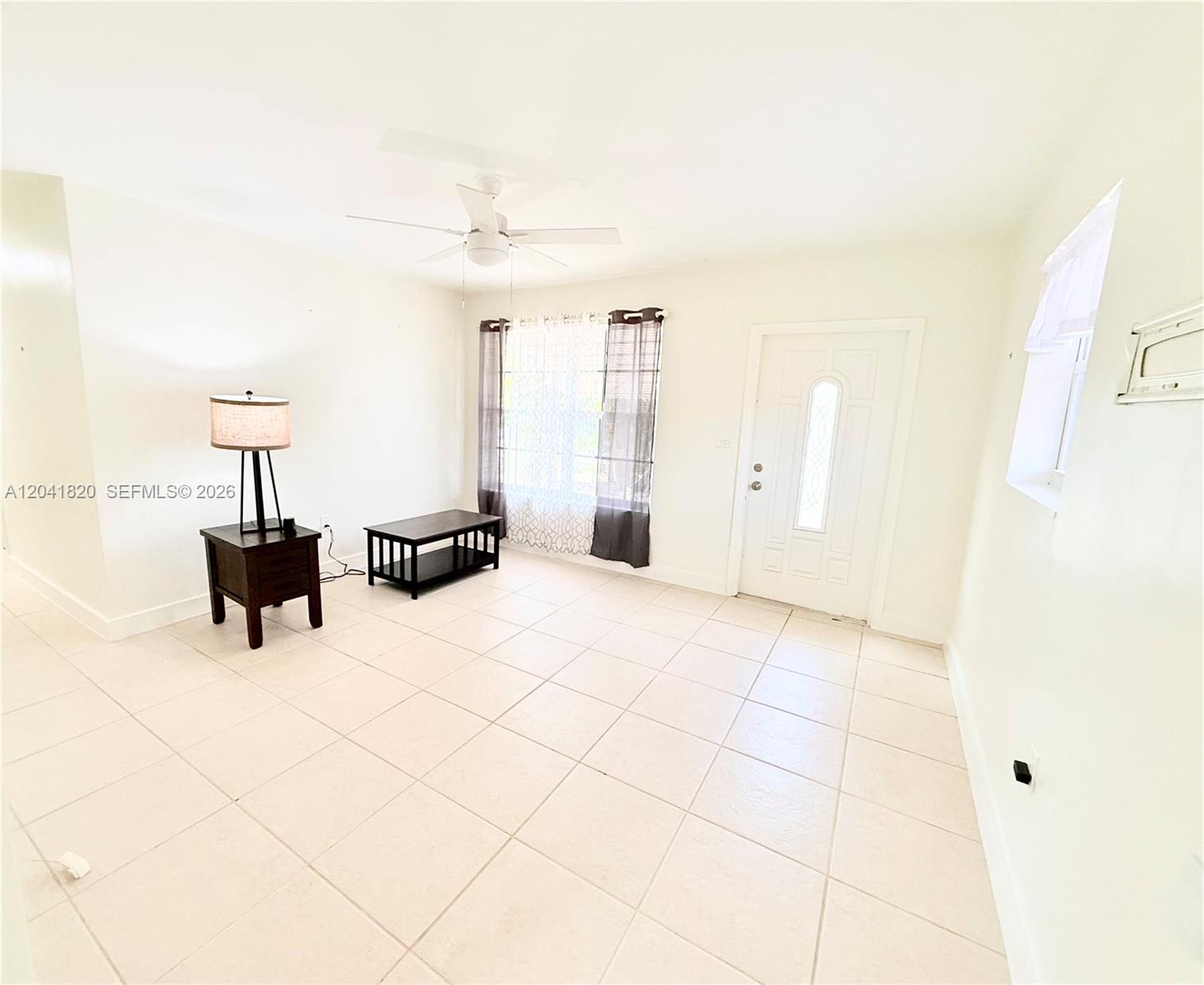 A bright living room features white walls, tiled floors, a ceiling fan, and a front door — 1311 N 69th Ave, Hollywood FL 33024, HOLLYWOOD, FL