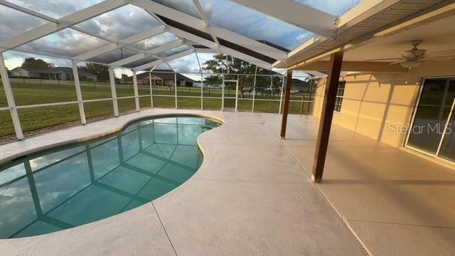 A screened-in pool patio features a kidney-shaped pool and a covered concrete deck area — 9300 COUNTY ROAD 128C, WILDWOOD, FL