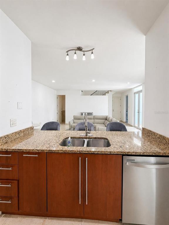 A kitchen with granite countertops and wood cabinets overlooks a living room with a sofa — TREASURE POINT CALLE AGUAMARINE UNIT 13, VEGA ALTA, PR
