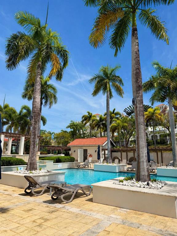 A swimming pool surrounded by lounge chairs, palm trees, and a small building under blue skies — TREASURE POINT CALLE AGUAMARINE UNIT 13, VEGA ALTA, PR