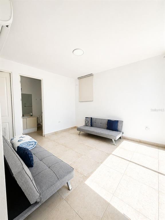 A room with light tile floors, white walls, and two gray futon sofas — TREASURE POINT CALLE AGUAMARINE UNIT 13, VEGA ALTA, PR