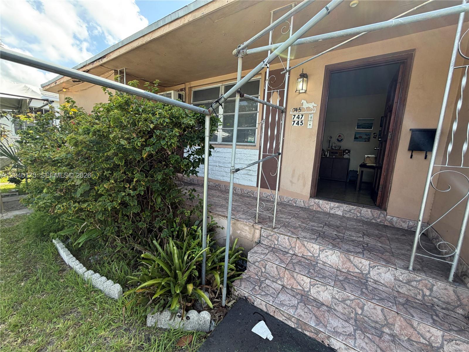 The exterior of a house features a tiled porch, metal awning supports, and a front door — 745 NW 32nd Ave, Miami FL 33125, MIAMI, FL