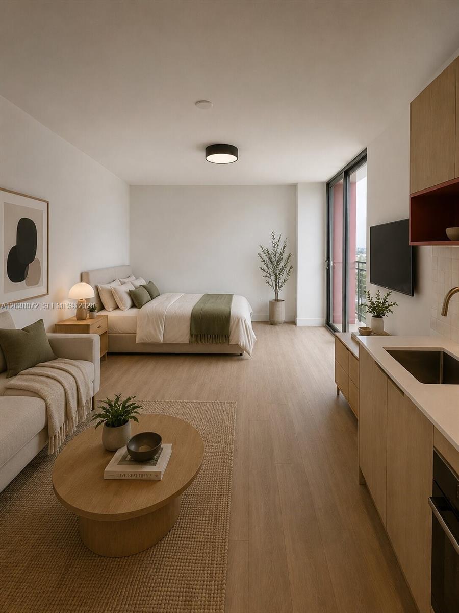 A studio apartment features a kitchenette, living area, and bed with light wood flooring — 90 NE 32nd St # 615, Miami FL 33127, MIAMI, FL