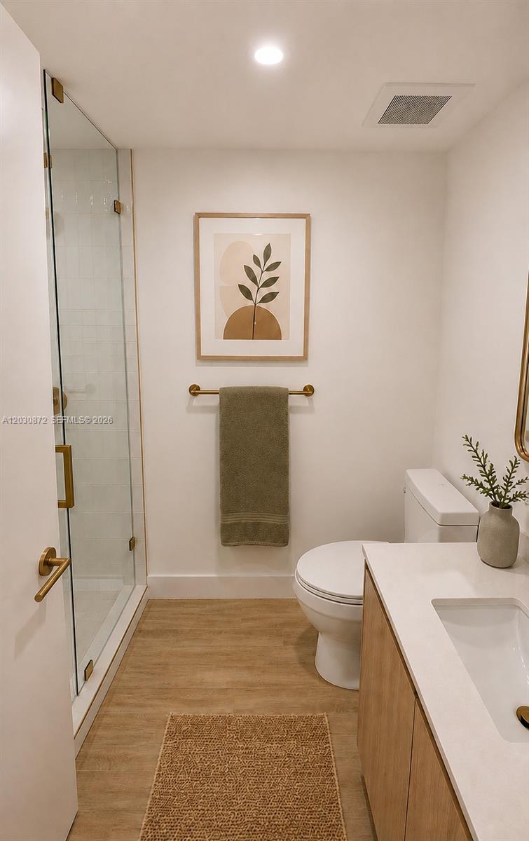 This bathroom features a glass-enclosed shower, a vanity, a toilet, and neutral decor — 90 NE 32nd St # 615, Miami FL 33127, MIAMI, FL
