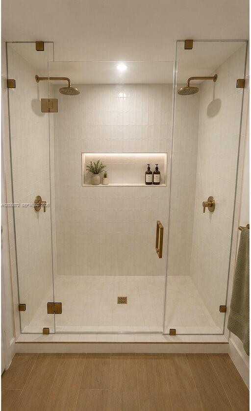 A walk-in shower with white tiled walls, gold fixtures, and a recessed lit niche — 90 NE 32nd St # 615, Miami FL 33127, MIAMI, FL