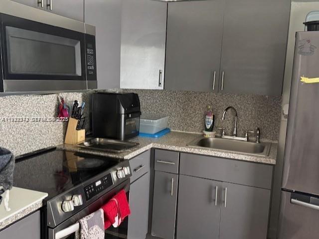 A kitchen features gray cabinets, stainless steel appliances, and a speckled countertop — 67 NW 34th St, Miami FL 33127, MIAMI, FL