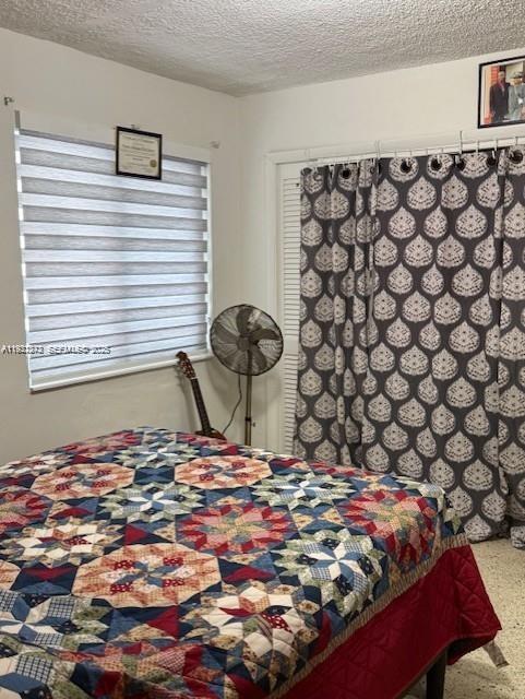 A bedroom features a patterned quilt on a bed, a window with blinds, and curtains — 67 NW 34th St, Miami FL 33127, MIAMI, FL