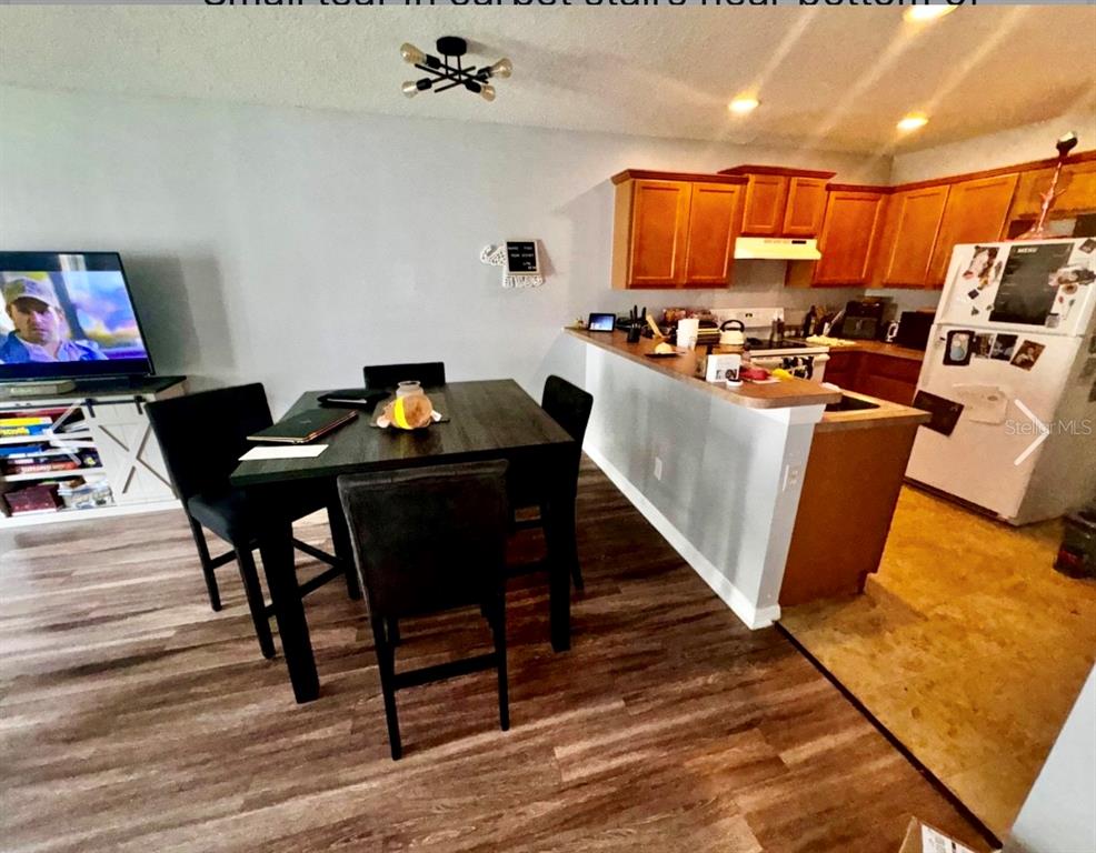 An open living area features wood-look flooring, gray walls, and a view of the kitchen — 533 CRESTING OAK CIRCLE UNIT 79, ORLANDO, FL