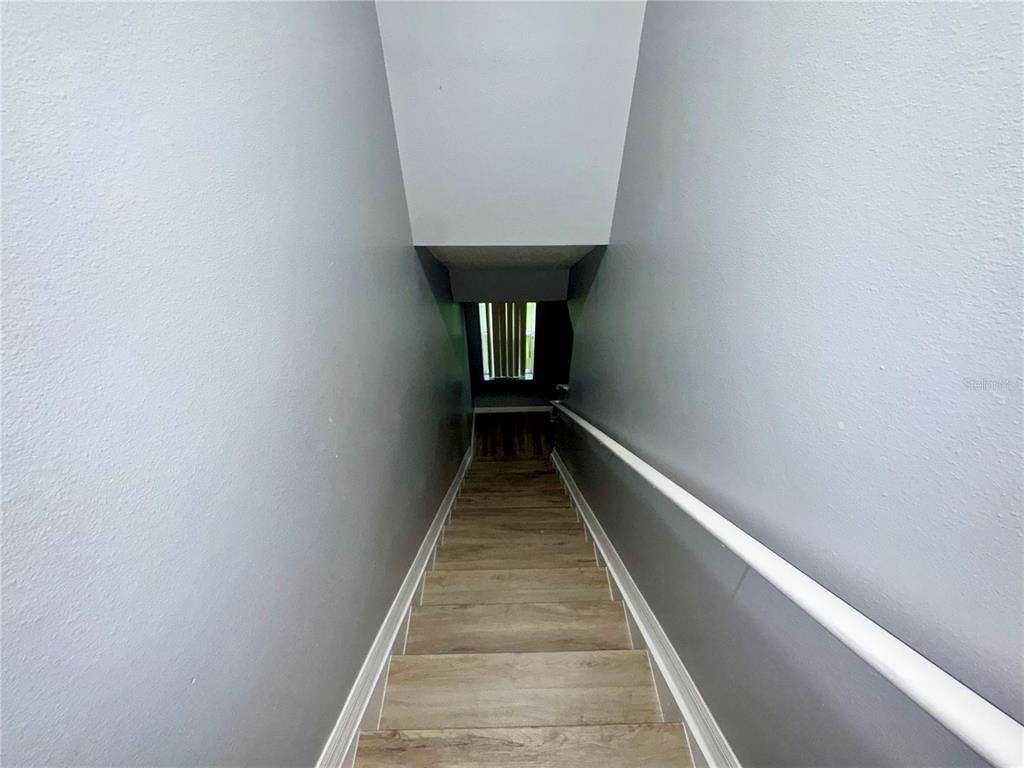 A downward view of a staircase with wood-look flooring, gray walls, and a white handrail — 533 CRESTING OAK CIRCLE UNIT 79, ORLANDO, FL