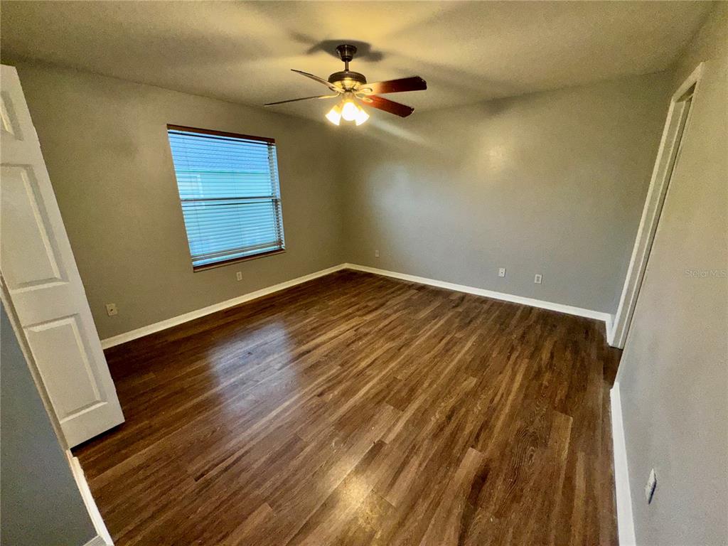 An empty bedroom features gray walls, wood-look flooring, a ceiling fan, and a single window — 533 CRESTING OAK CIRCLE UNIT 79, ORLANDO, FL
