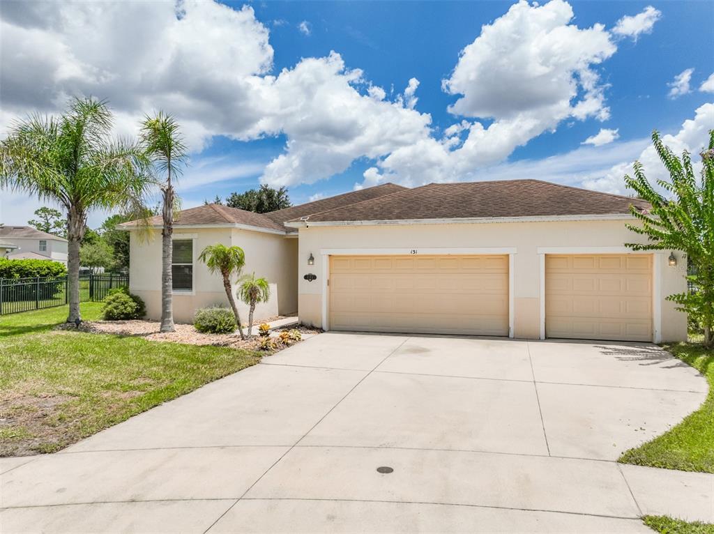 A single-story house with a beige exterior, a two-car garage, and a concrete driveway — 131 MULBERRY BRANCH COURT, DAYTONA BEACH, FL