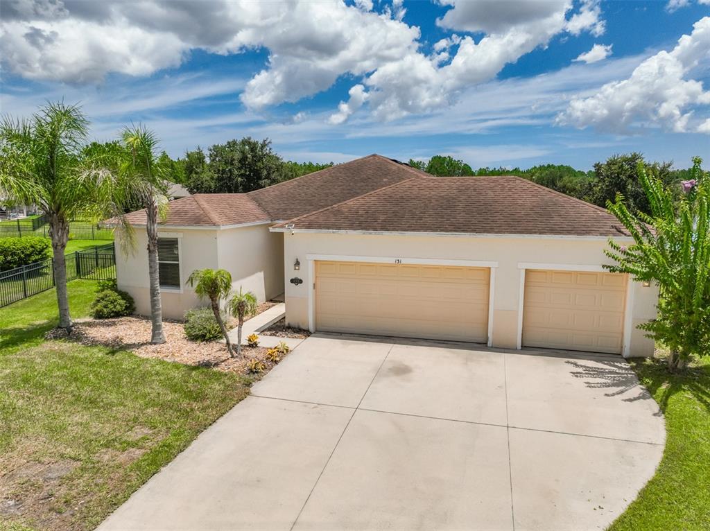 A single-story house with a beige stucco exterior, a two-car garage, and a concrete driveway — 131 MULBERRY BRANCH COURT, DAYTONA BEACH, FL