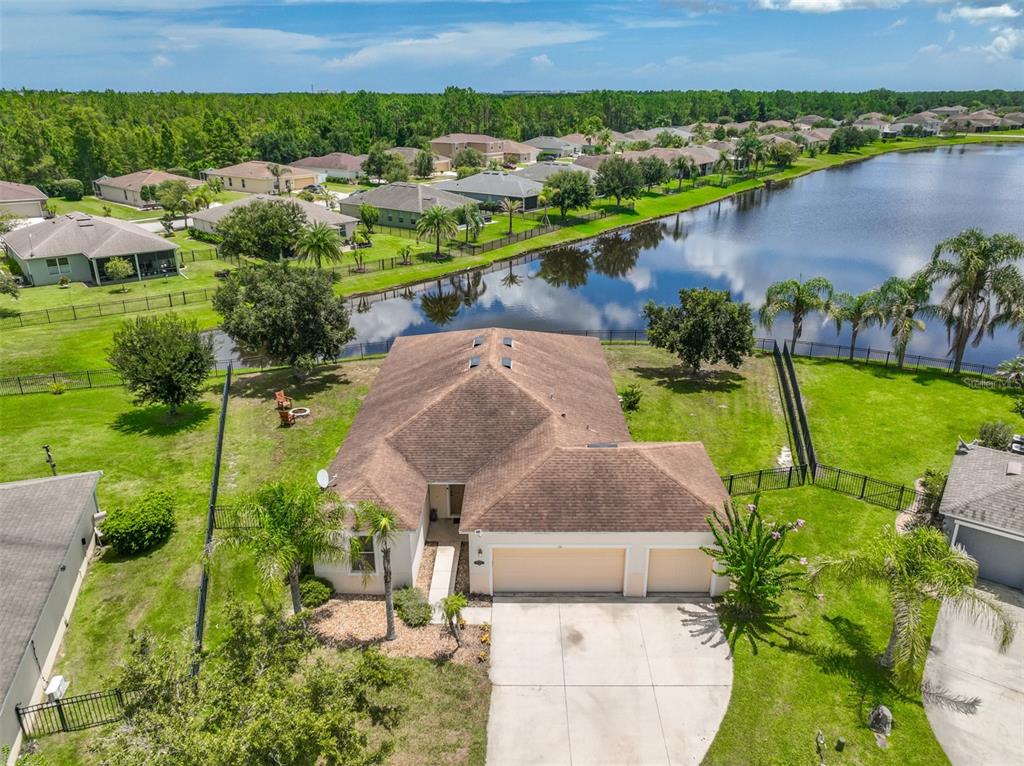 An aerial view shows a single-story house with a brown roof, garage, and backyard pond — 131 MULBERRY BRANCH COURT, DAYTONA BEACH, FL