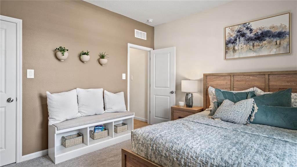 A bedroom features a wooden bed frame, a white storage bench, and wall-mounted planters — 183 GLENFIELD DRIVE, DAVENPORT, FL