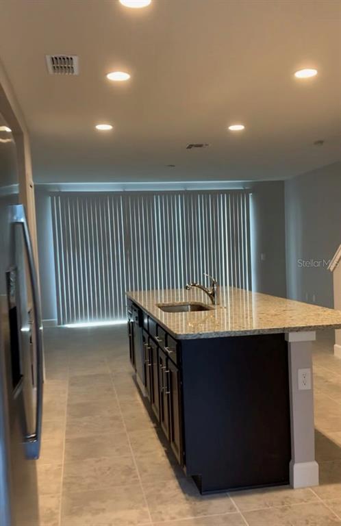 A kitchen island with a granite countertop and dark cabinets sits in a tiled room — 4702 TERRA ESMERALDA DRIVE, KISSIMMEE, FL