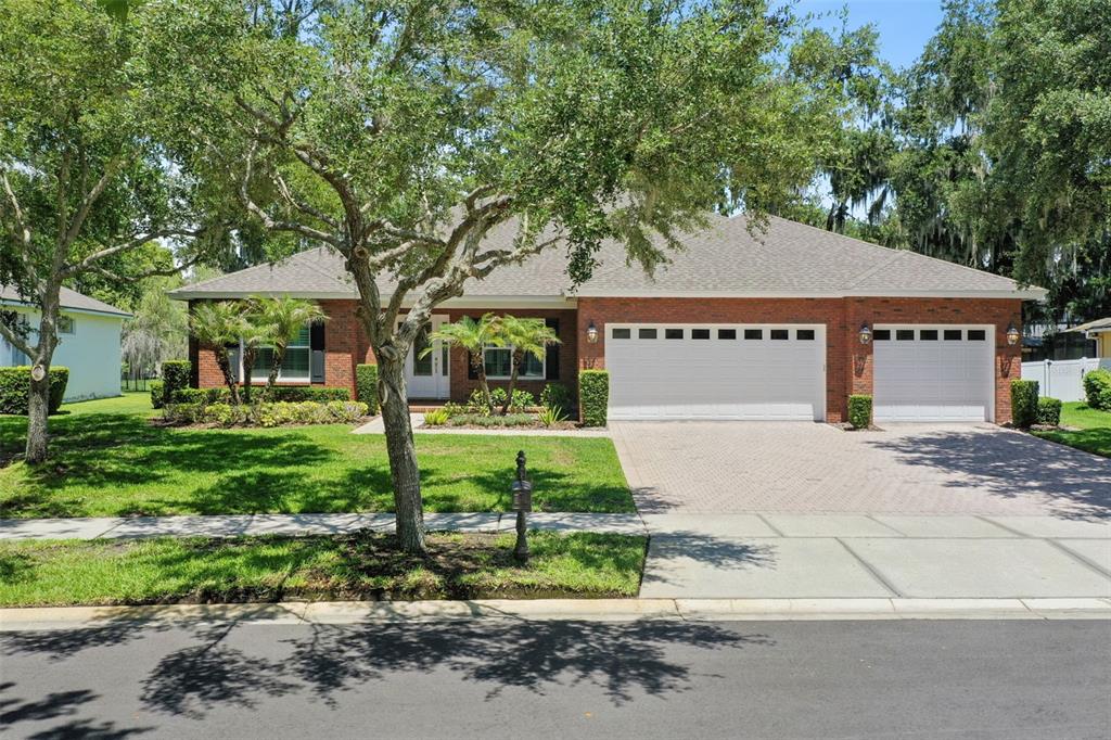 A single-story brick house with a three-car garage and a paved driveway — 440 TIERRA VERDE LANE, WINTER GARDEN, FL