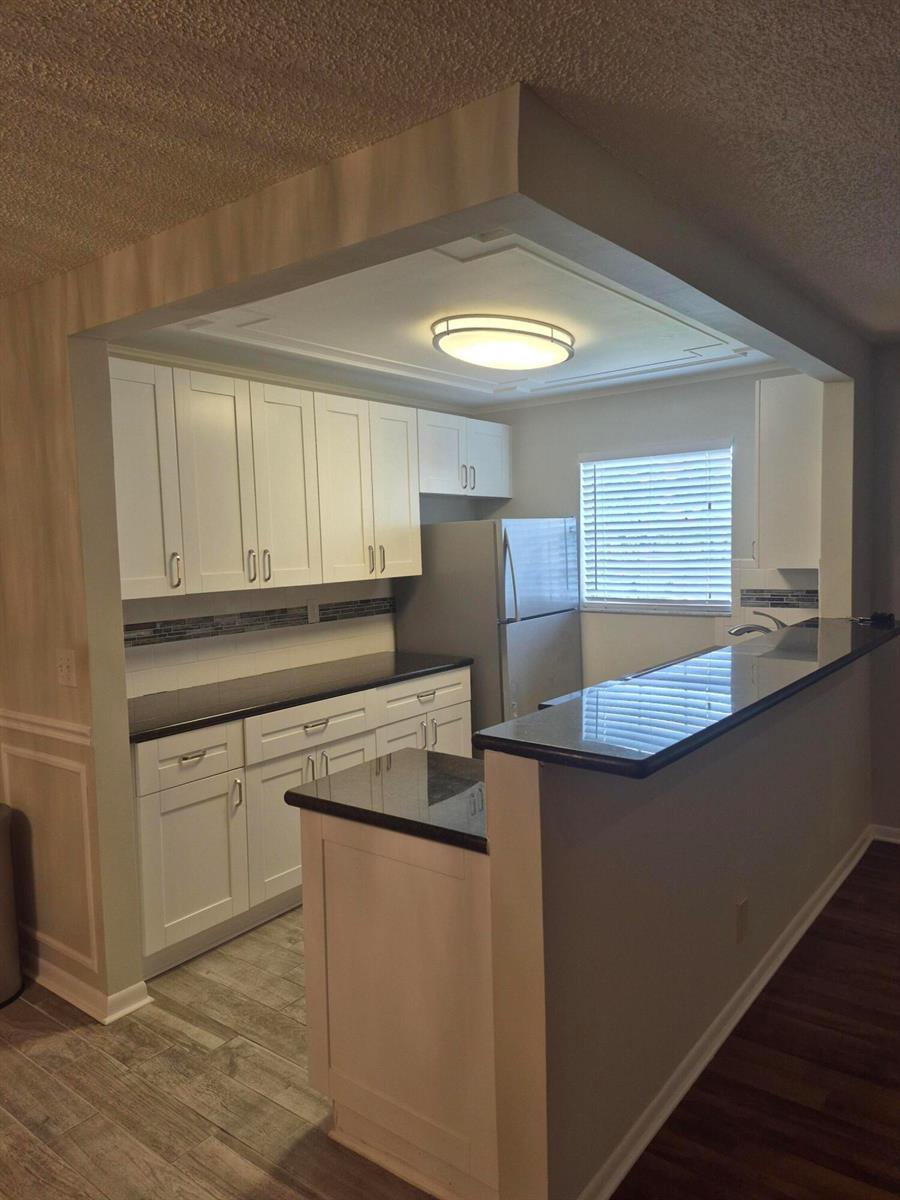 A kitchen features white cabinets, black countertops, a breakfast bar, and a recessed ceiling light — 4530 NW 3rd Street # B, Delray Beach FL 33445, DELRAY BEACH, FL
