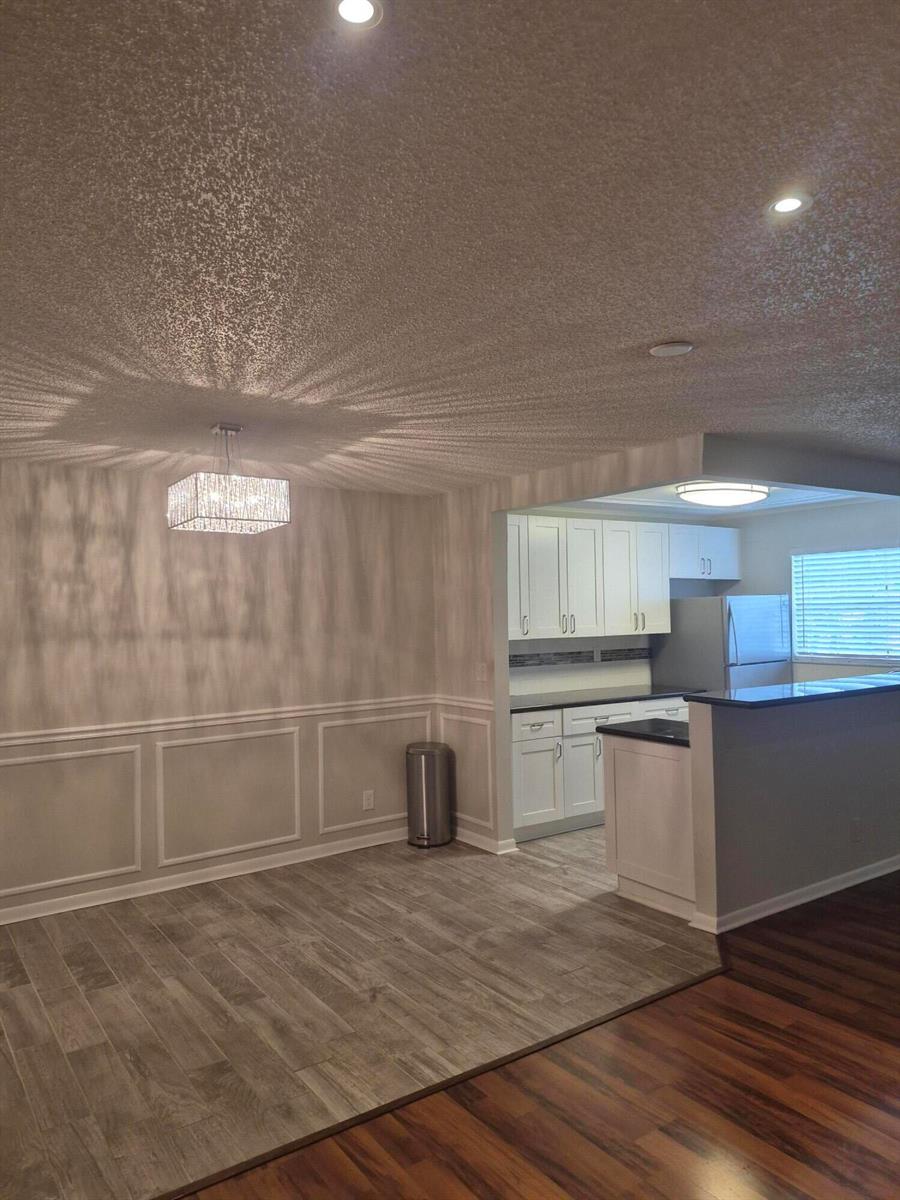 A dining area with wainscoting and a crystal chandelier opens into a white kitchen — 4530 NW 3rd Street # B, Delray Beach FL 33445, DELRAY BEACH, FL