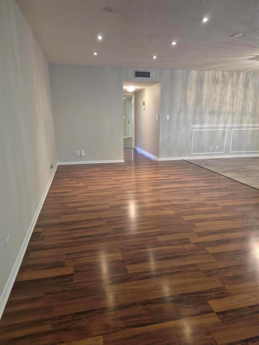 A room with wood-look laminate flooring, recessed lighting, and a doorway leading to a hallway — 4530 NW 3rd Street # B, Delray Beach FL 33445, DELRAY BEACH, FL