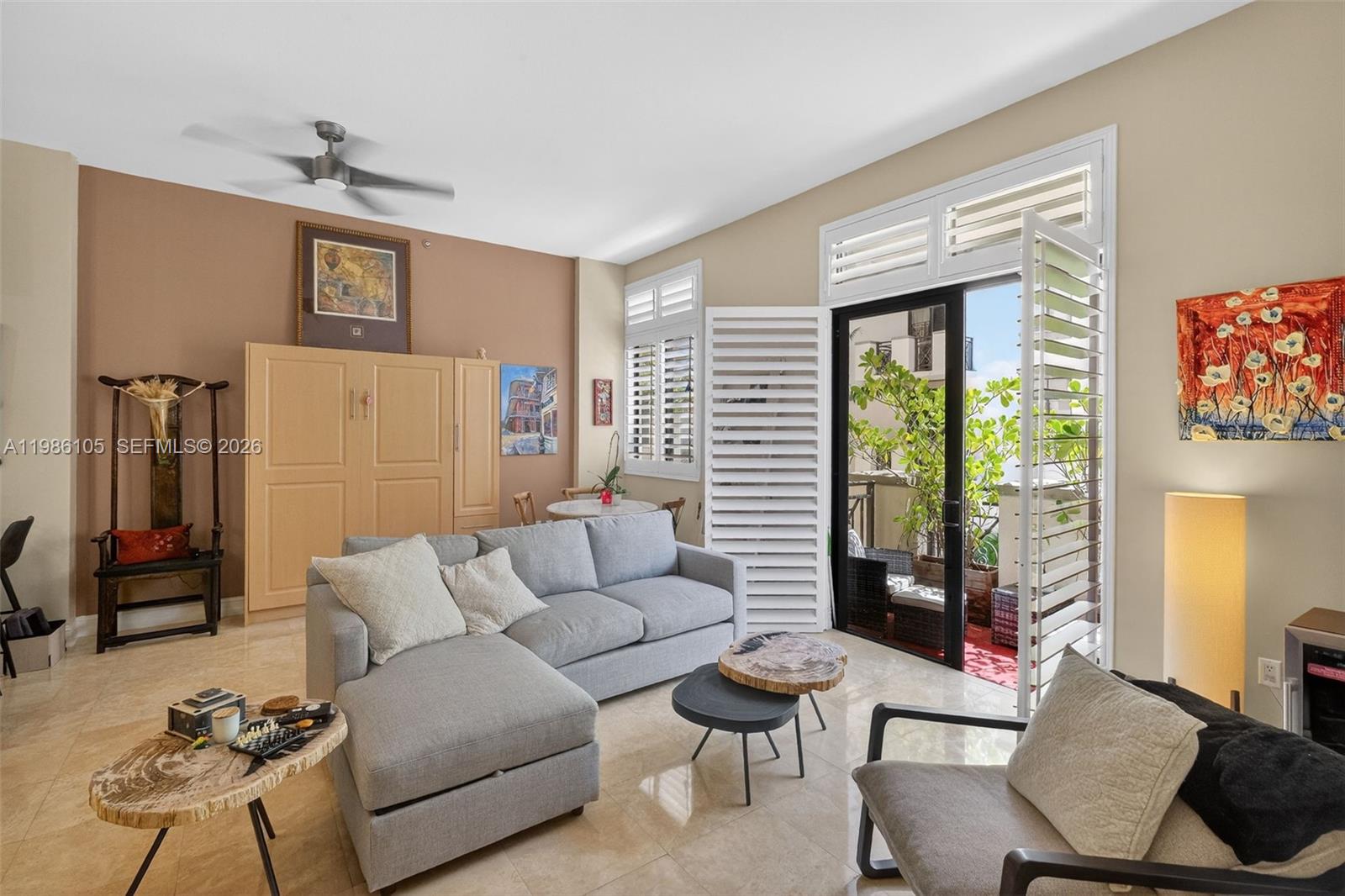 A living room features a gray sectional sofa, a balcony, and light-colored tile flooring — 1805 Ponce De Leon Blvd # 616, Coral Gables FL 33134, CORAL GABLES, FL