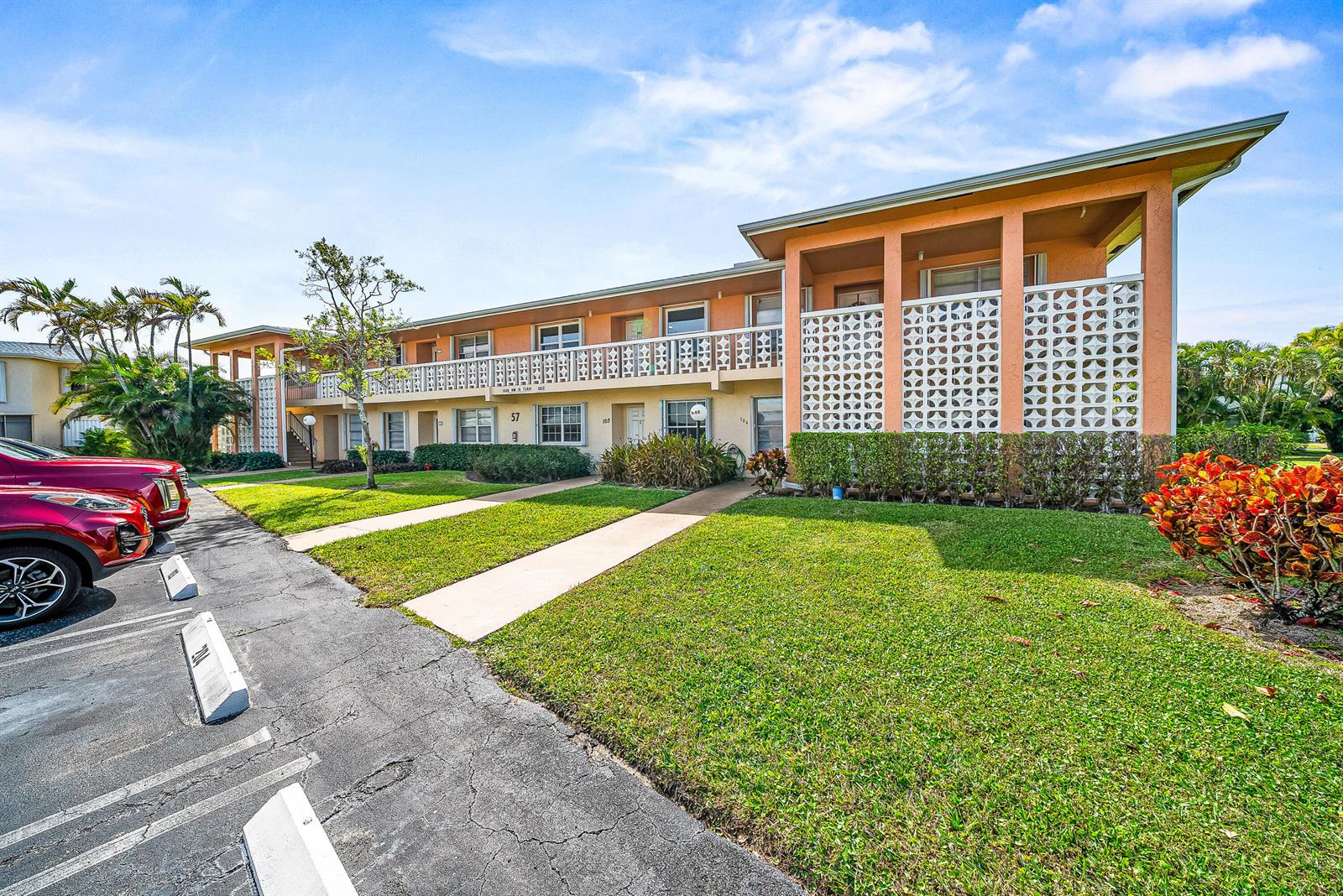 A two-story apartment building with peach-colored walls, decorative breeze block screens, and a parking lot — 1640 NW 19TH Terrace # 203, Delray Beach FL 33445, DELRAY BEACH, FL