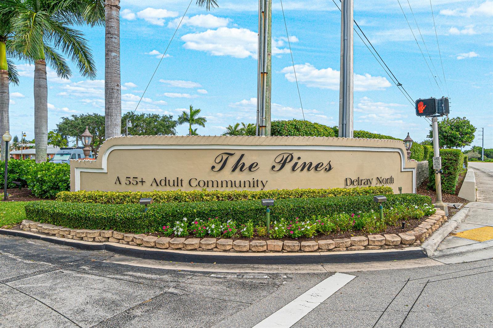 The entrance sign for The Pines 55+ adult community features landscaping and a traffic light — 1640 NW 19TH Terrace # 203, Delray Beach FL 33445, DELRAY BEACH, FL