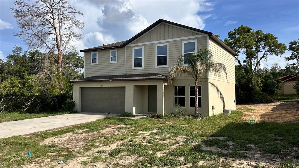 A two-story house with tan siding, a two-car garage, and a palm tree in front — 3427 HARTLEY ROAD, SPRING HILL, FL