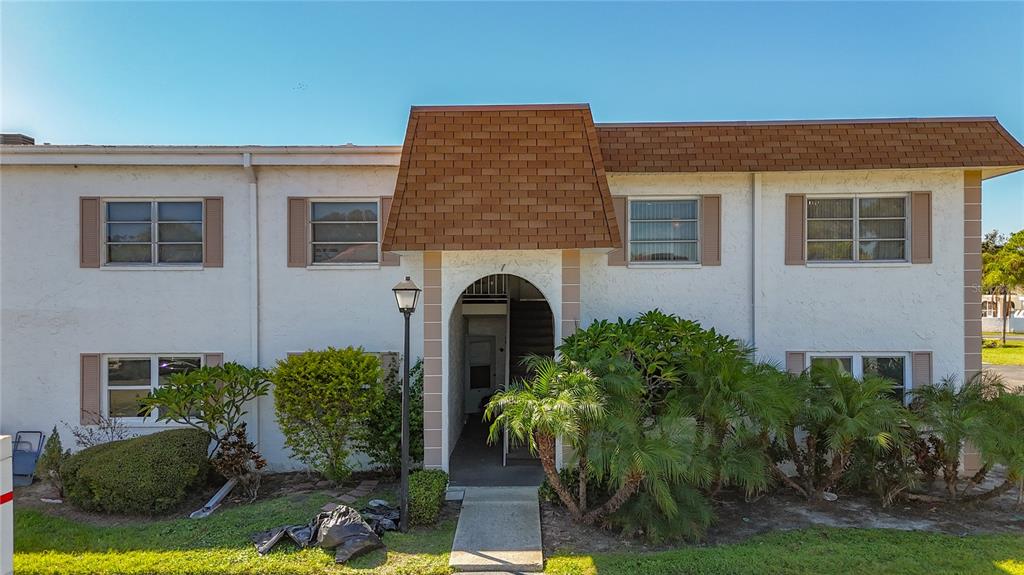 A two-story apartment building with a brown shingled roof and a central arched entryway — 379 S MCMULLEN BOOTH ROAD UNIT 76, CLEARWATER, FL