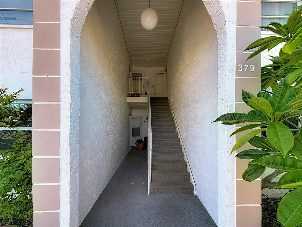 An outdoor stairwell leads to two entry doors under a white arched entryway — 379 S MCMULLEN BOOTH ROAD UNIT 76, CLEARWATER, FL
