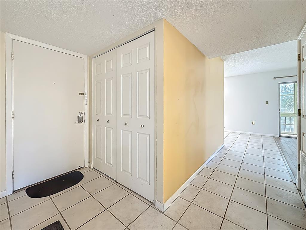 An entryway features a white front door, a bi-fold closet, and light-colored floor tiles — 379 S MCMULLEN BOOTH ROAD UNIT 76, CLEARWATER, FL