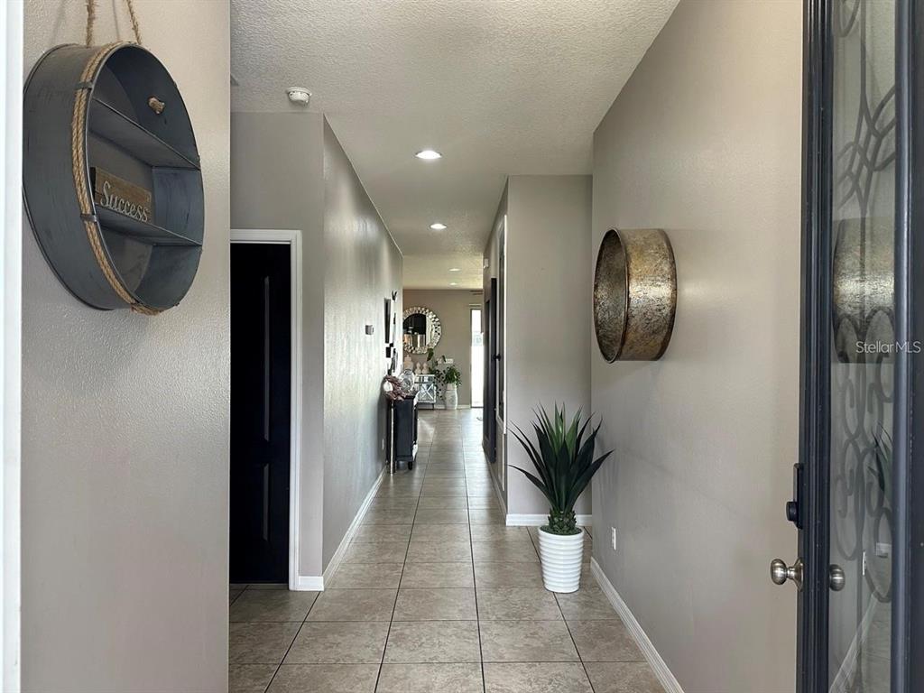 A tiled hallway features gray walls, recessed lighting, and decorative wall-mounted circular accents — 12254 SANDY APPLE ROAD, ORLANDO, FL