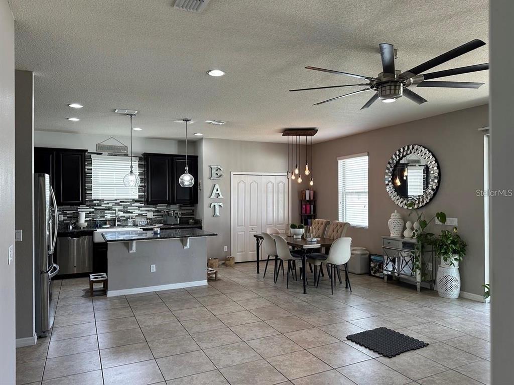 An open-concept kitchen and dining area features dark cabinetry, tile flooring, and a ceiling fan — 12254 SANDY APPLE ROAD, ORLANDO, FL