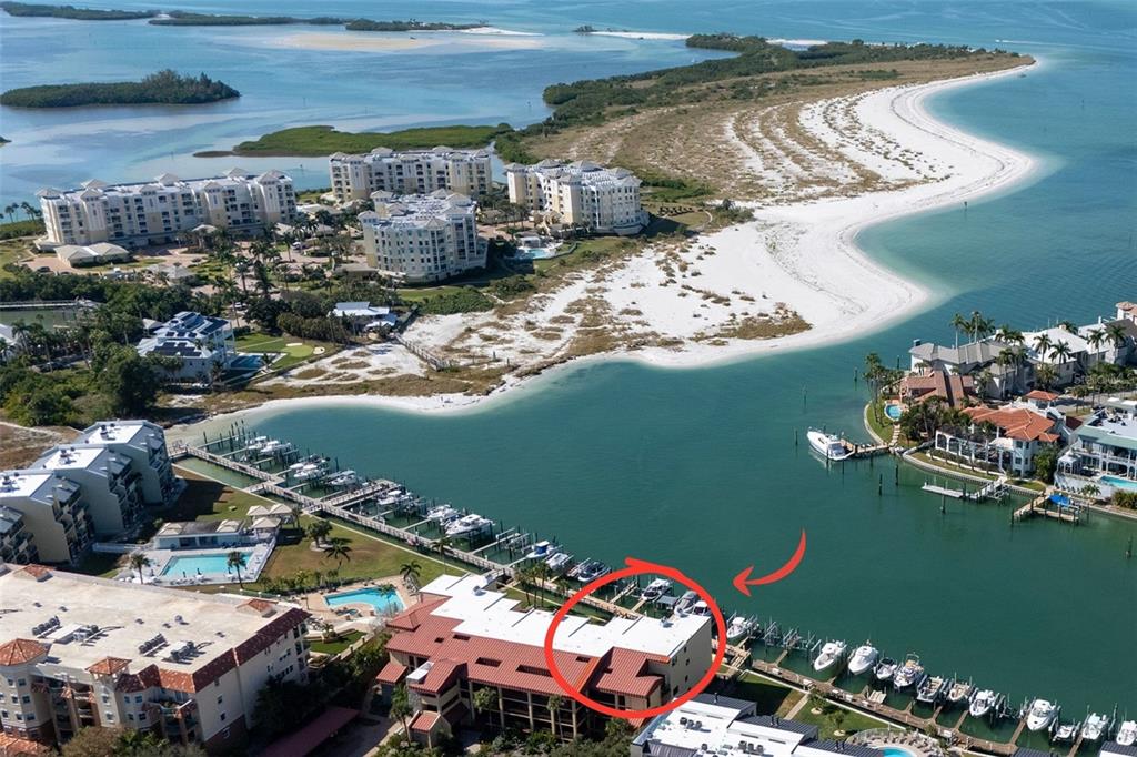An aerial view shows a multi-story waterfront condominium building with an adjacent boat slip marina — 1060 PINELLAS BAYWAY S UNIT 106, TIERRA VERDE, FL