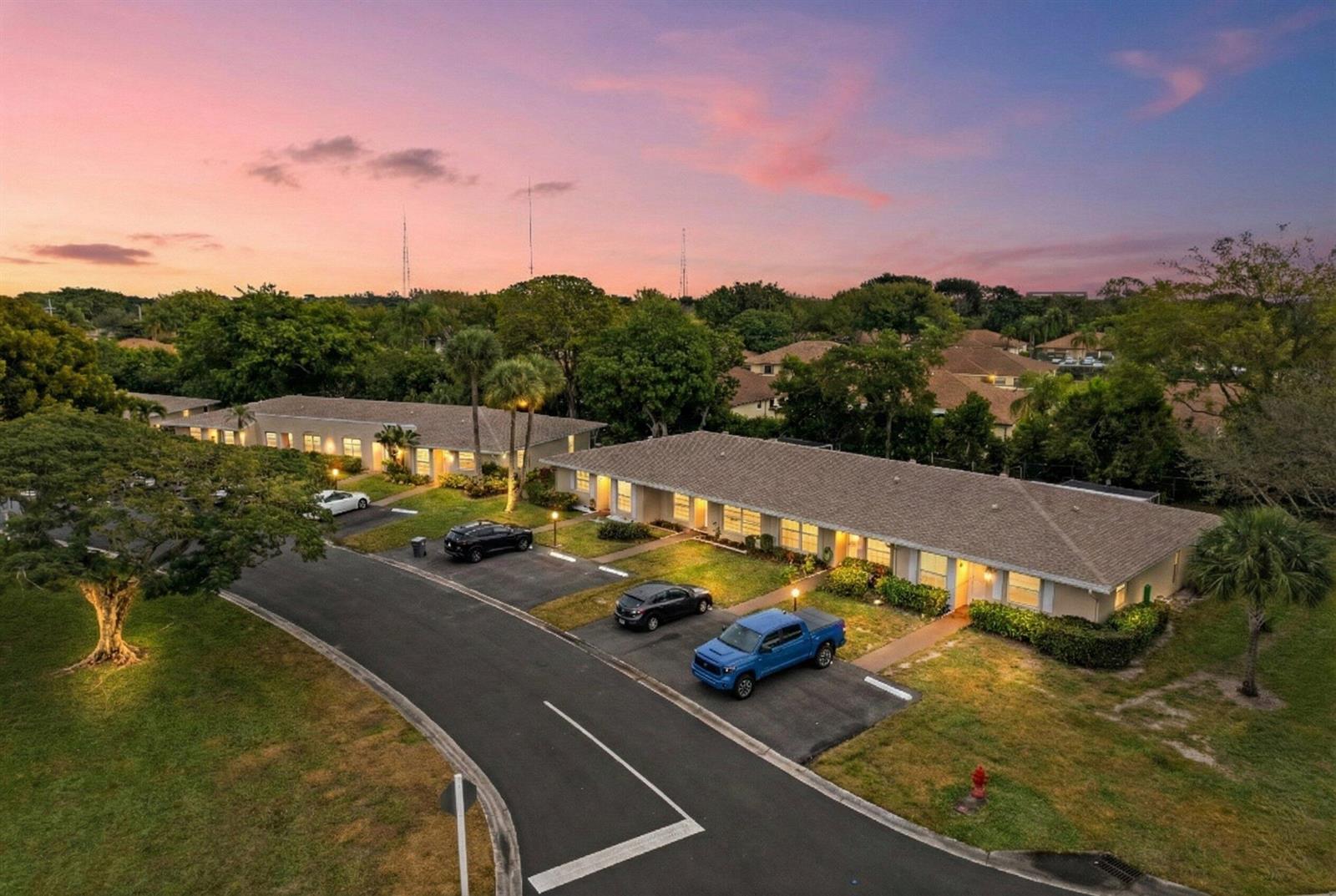 An aerial view shows two single-story apartment buildings with parking spaces at sunset — 8555 Bella Vista Drive # 86, Boca Raton FL 33433, BOCA RATON, FL