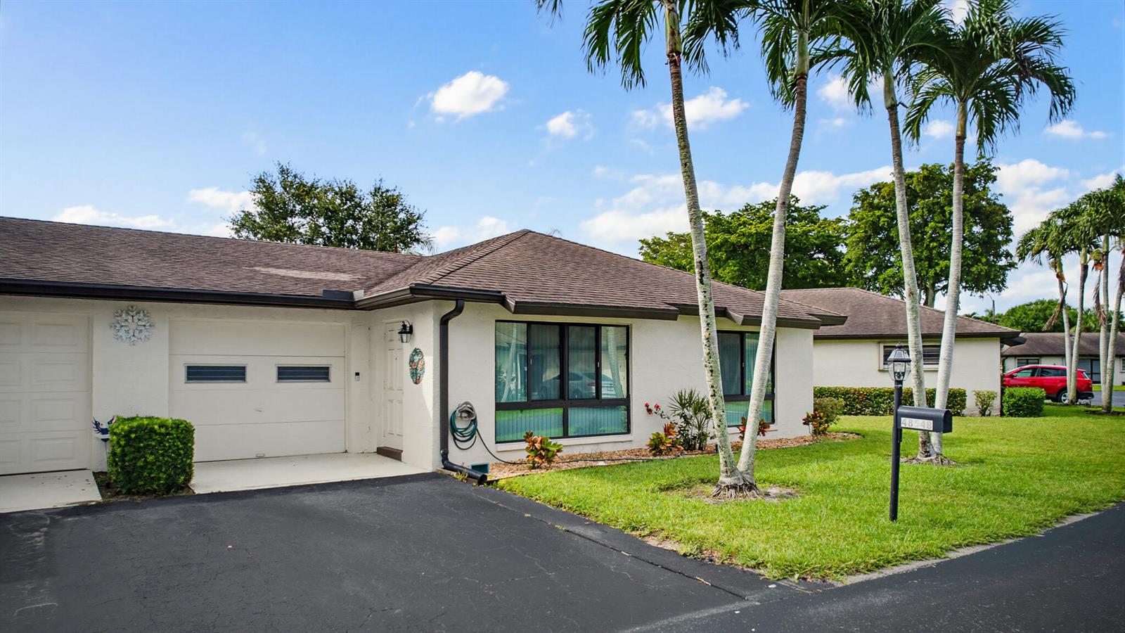 A single-story white house with a garage, palm trees, and a lawn under a blue sky — 4854 Equestrian Circle Apt B, Boynton Beach FL 33436, BOYNTON BEACH, FL