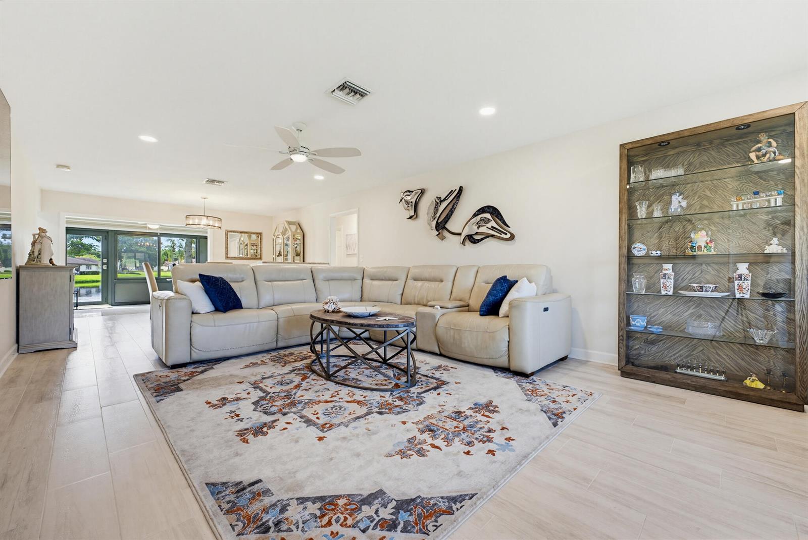 A living room features a large beige sectional, a patterned area rug, and a display cabinet — 4854 Equestrian Circle Apt B, Boynton Beach FL 33436, BOYNTON BEACH, FL
