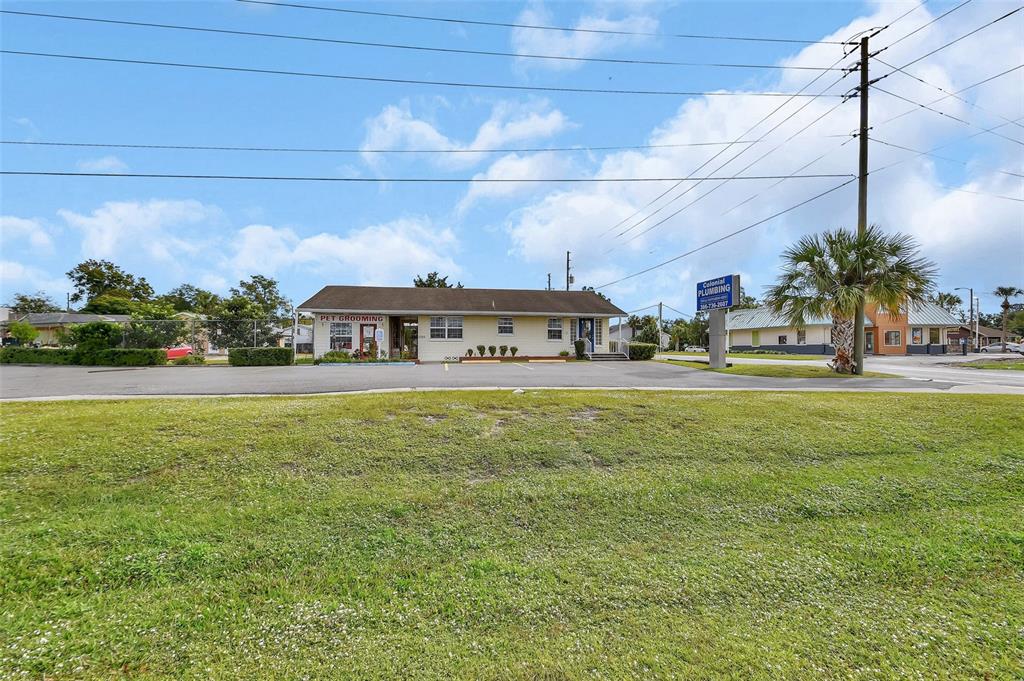A single-story commercial building with a pet grooming business and a plumbing sign outside — 1319 S WOODLAND BOULEVARD, DELAND, FL