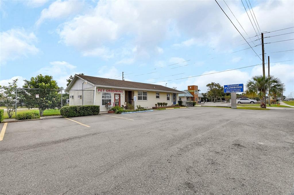 A single-story commercial building with a pet grooming sign sits in a paved parking lot — 1319 S WOODLAND BOULEVARD, DELAND, FL