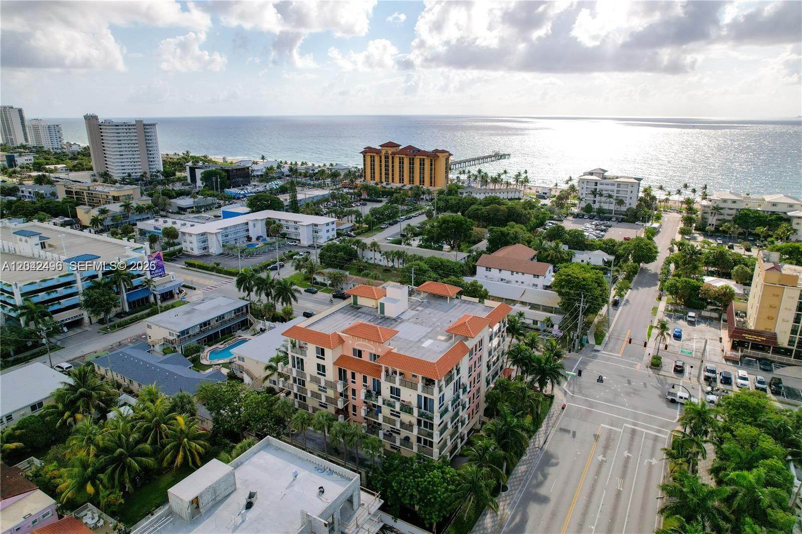 An aerial view shows a coastal neighborhood with multi-story buildings, palm trees, and a pier — 9 NE 20th Ave # 201, Deerfield Beach FL 33441, DEERFIELD BEACH, FL
