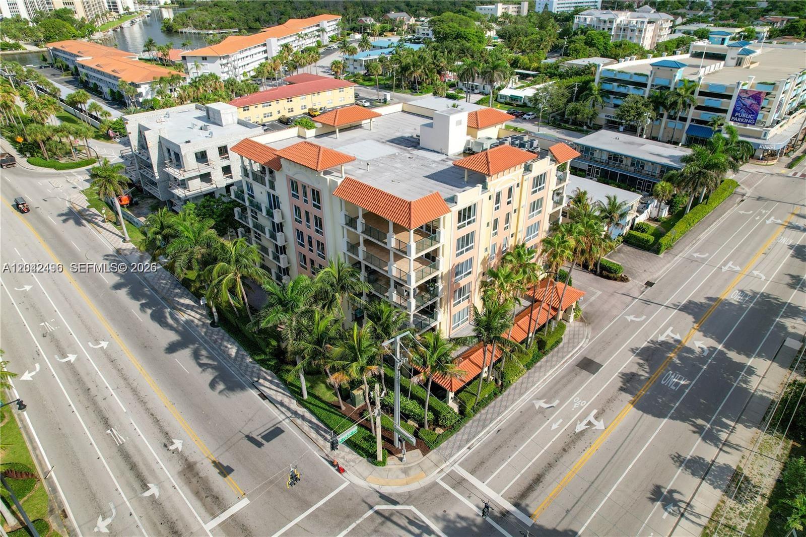 An aerial view shows a multi-story apartment building with a terracotta roof at an intersection — 9 NE 20th Ave # 201, Deerfield Beach FL 33441, DEERFIELD BEACH, FL