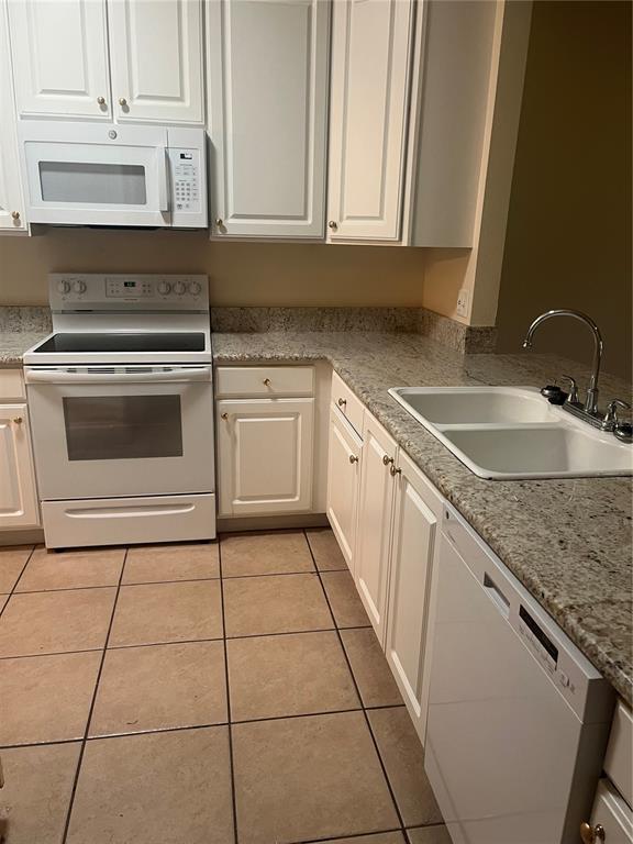 A kitchen features white cabinets, white appliances, speckled granite countertops, and light-colored tile flooring — 8509 ALEXANDRA ARBOR LANE, TAMPA, FL