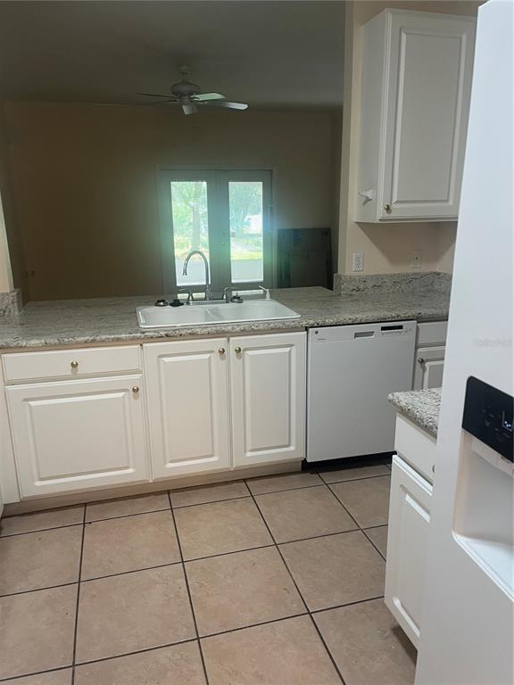 A kitchen features white cabinets, granite countertops, a double sink, and tile flooring — 8509 ALEXANDRA ARBOR LANE, TAMPA, FL