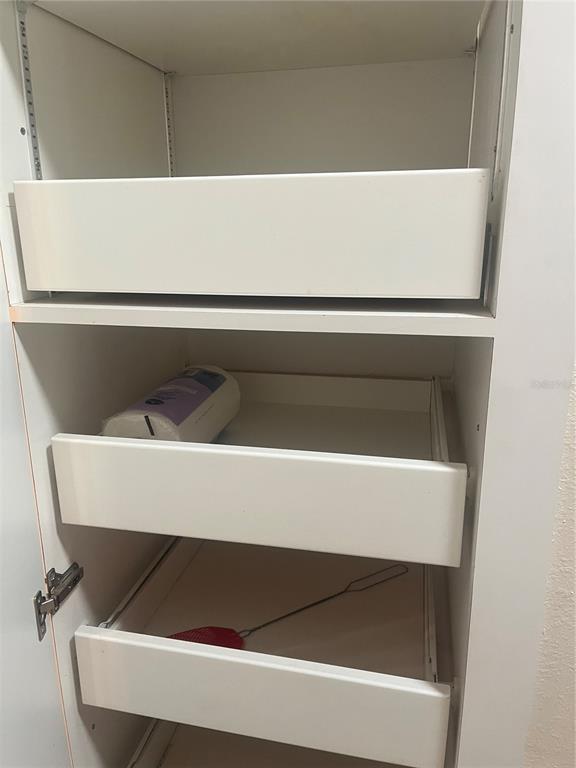 A white pantry cabinet features three pull-out shelves with a paper towel roll and utensil — 8509 ALEXANDRA ARBOR LANE, TAMPA, FL